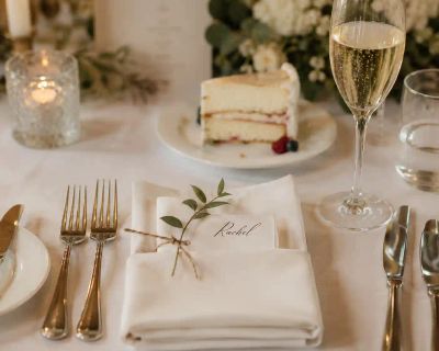A table set for the wedding breakfast, with a glass of sparkling wine and a slice of cake.