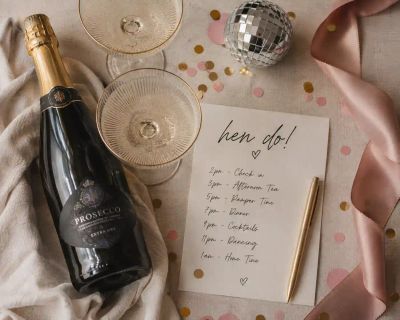 A celebratory table setting with glasses and a handwritten hen do itinerary card.