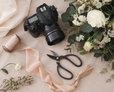 A camera, floristry shears, and ribbon arranged together, representing the wedding vendors and suppliers who help put the day together.