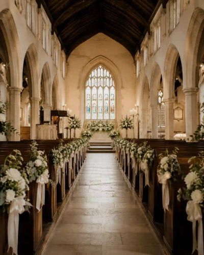 An empty church aisle softly lit, ready for a wedding ceremony.