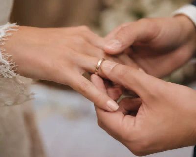 Close-up of two hands exchanging a wedding ring during a ceremony.