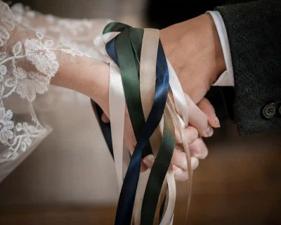 Ribbons tied around two joined hands during a hand-fasting ceremony.