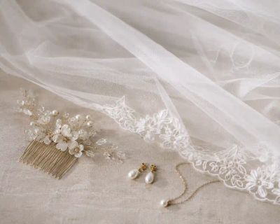 A bridal veil laid out beside a hair comb and simple jewellery.